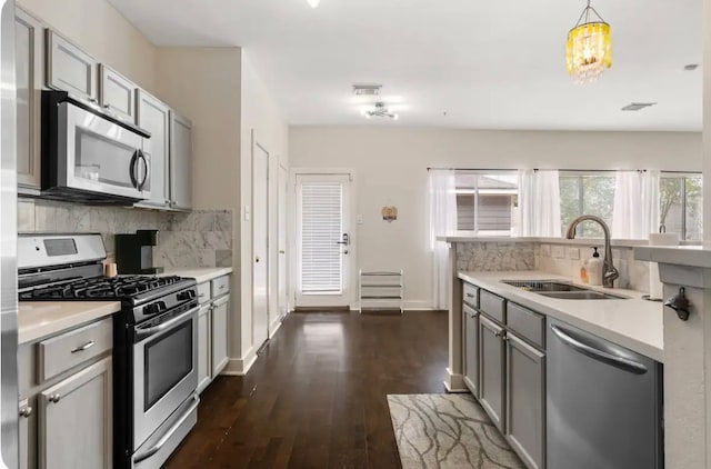 kitchen with appliances with stainless steel finishes, gray cabinets, decorative light fixtures, and sink