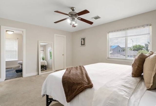 carpeted bedroom with ceiling fan, multiple windows, and ensuite bath