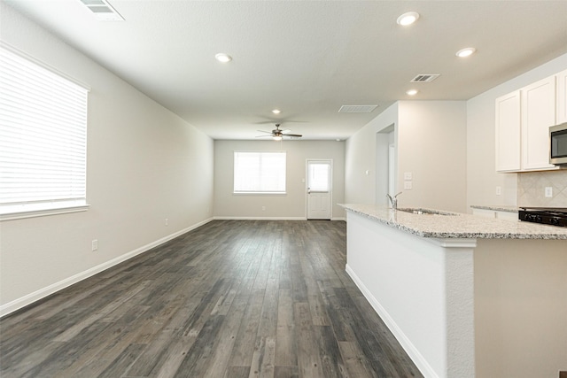 unfurnished living room featuring ceiling fan, dark wood-type flooring, and sink