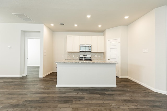 kitchen with a center island with sink, decorative backsplash, stove, and white cabinetry