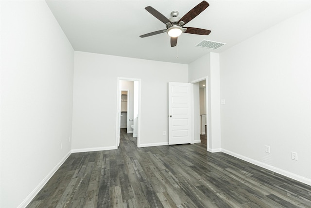 unfurnished bedroom featuring a closet, ceiling fan, dark wood-type flooring, and a spacious closet