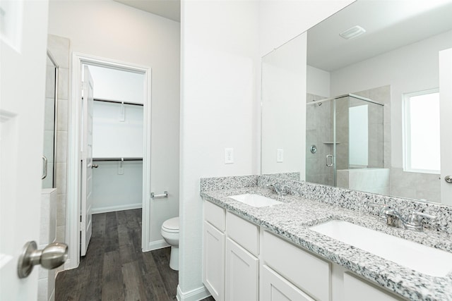 bathroom featuring vanity, hardwood / wood-style flooring, toilet, and a shower with door