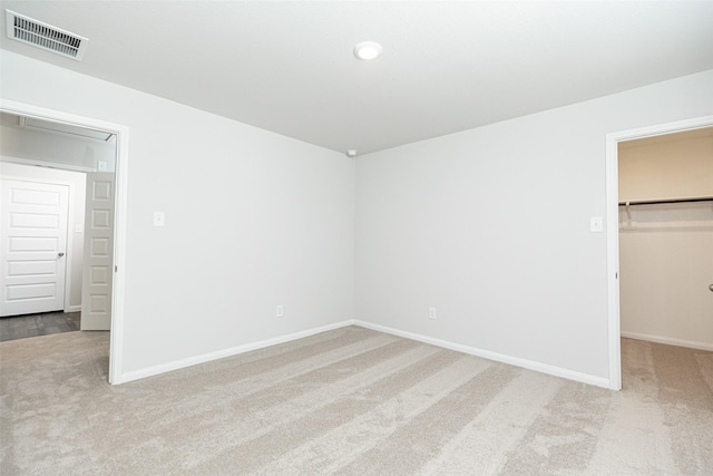 unfurnished bedroom featuring light carpet, a spacious closet, and a closet