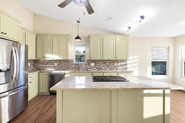 kitchen featuring appliances with stainless steel finishes, vaulted ceiling, a wealth of natural light, and light stone counters