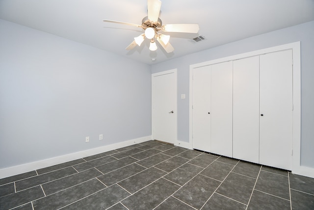 unfurnished bedroom featuring a closet, dark tile patterned flooring, and ceiling fan