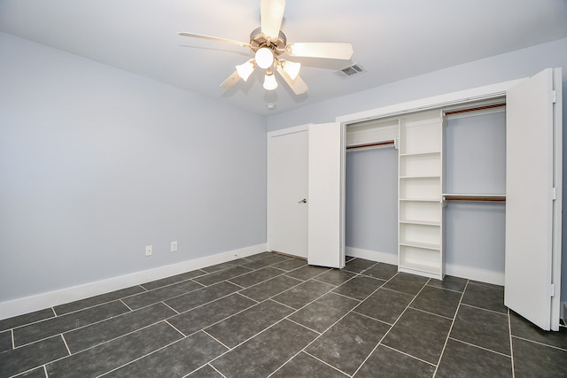 unfurnished bedroom featuring ceiling fan, a closet, and dark tile patterned floors