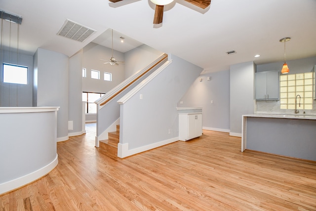 unfurnished living room featuring a wealth of natural light, sink, ceiling fan, and light hardwood / wood-style floors