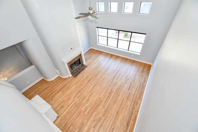 living room featuring a tile fireplace, ceiling fan, hardwood / wood-style floors, and a towering ceiling