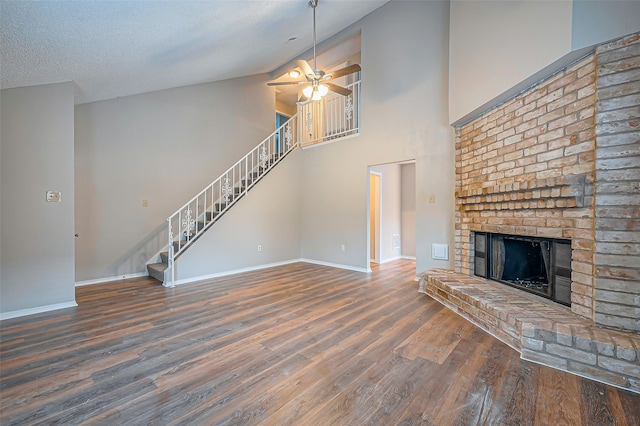 unfurnished living room featuring ceiling fan, high vaulted ceiling, dark hardwood / wood-style floors, a textured ceiling, and a fireplace