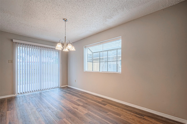 spare room featuring dark hardwood / wood-style floors, a textured ceiling, and a chandelier