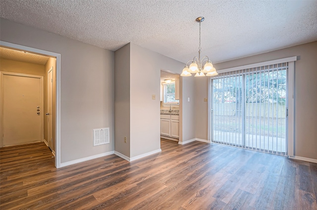 unfurnished dining area with dark hardwood / wood-style floors, a textured ceiling, and a chandelier