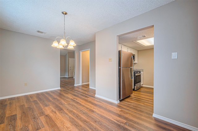 interior space featuring dark wood-type flooring, stainless steel appliances, a textured ceiling, decorative light fixtures, and white cabinets