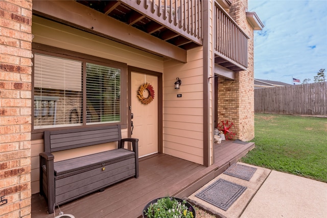 view of exterior entry with a lawn and a wooden deck