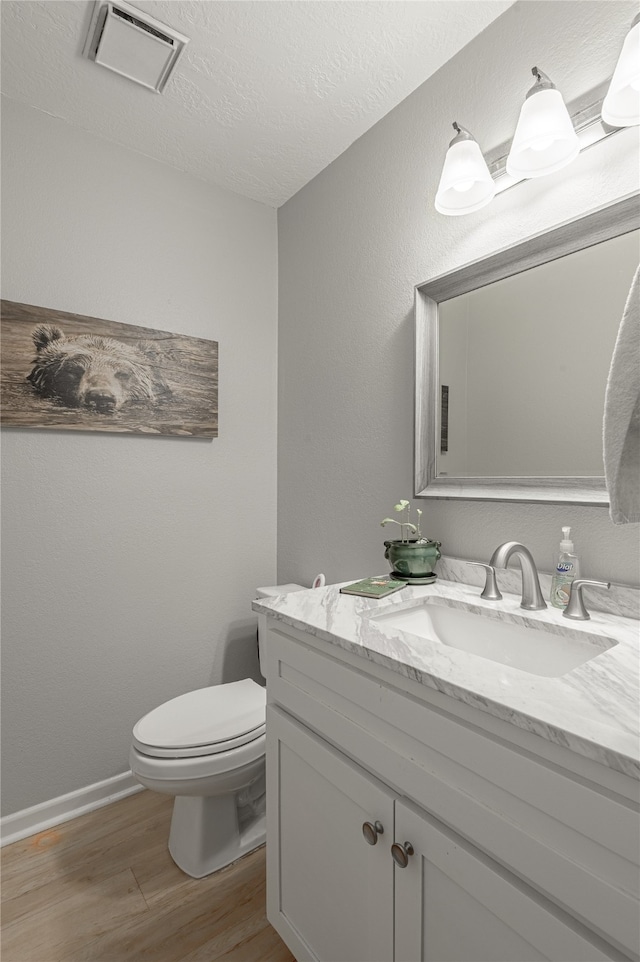 bathroom featuring hardwood / wood-style flooring, vanity, toilet, and a textured ceiling