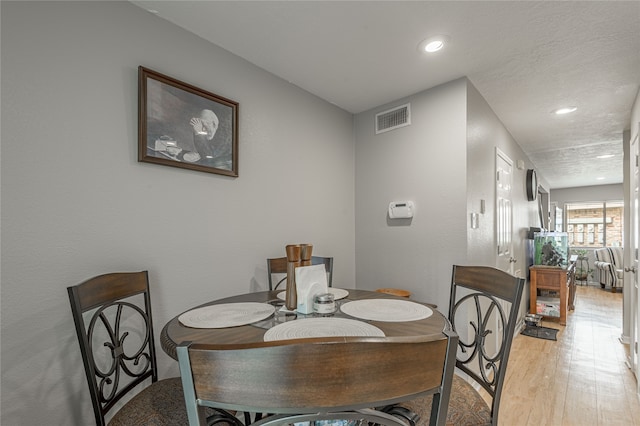 dining area with a textured ceiling and light wood-type flooring