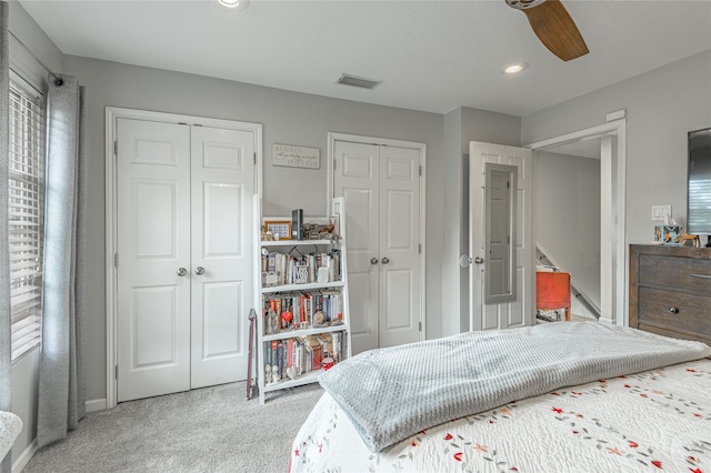 carpeted bedroom featuring ceiling fan and two closets