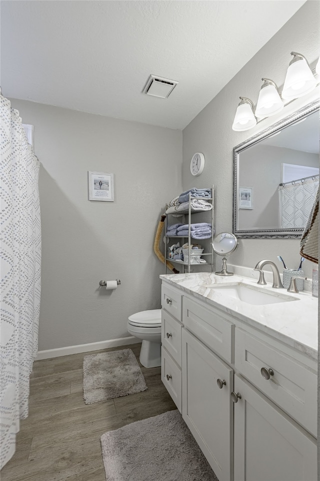 bathroom with wood-type flooring, vanity, and toilet