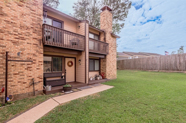 rear view of property with a balcony and a lawn