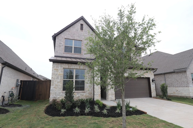 view of front of house featuring a standing seam roof, stone siding, concrete driveway, fence, and an attached garage