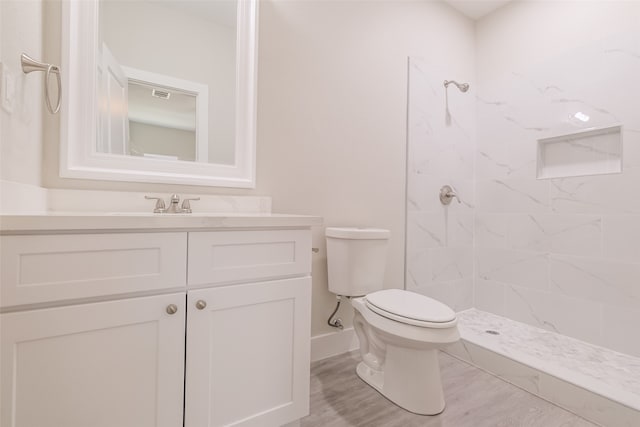 bathroom with vanity, toilet, and tiled shower