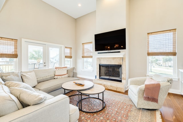 living room featuring plenty of natural light, a towering ceiling, and light hardwood / wood-style floors