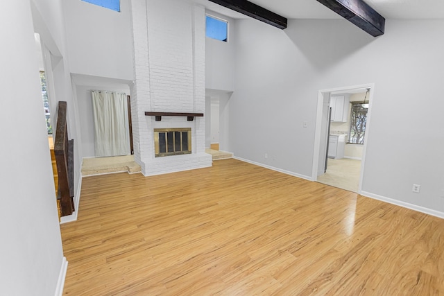 unfurnished living room featuring a brick fireplace, high vaulted ceiling, beamed ceiling, and light wood-type flooring