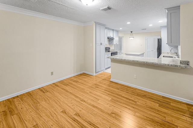 kitchen featuring sink, white cabinets, fridge, a textured ceiling, and light hardwood / wood-style flooring