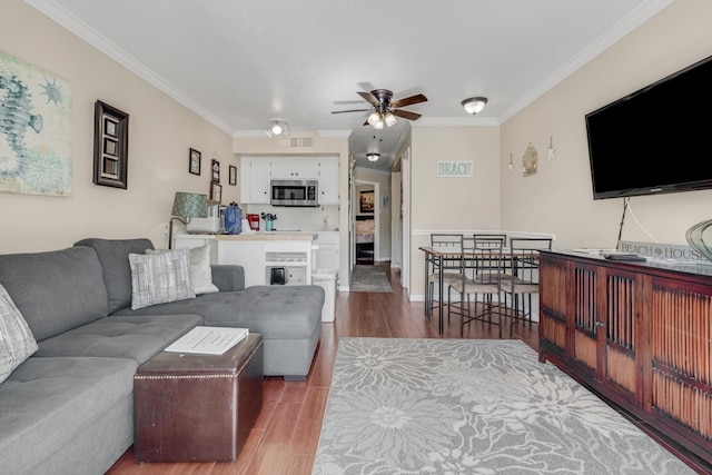 living room featuring hardwood / wood-style flooring, ceiling fan, and ornamental molding