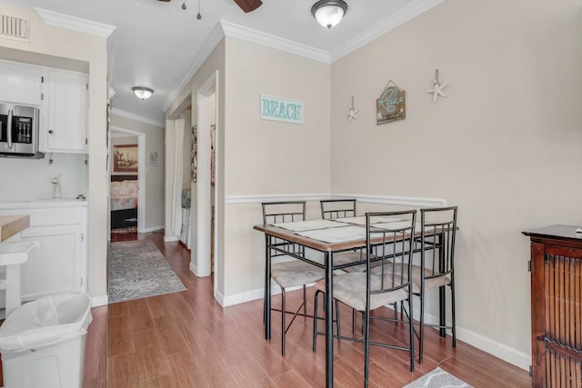 dining room with crown molding, sink, ceiling fan, and light hardwood / wood-style floors