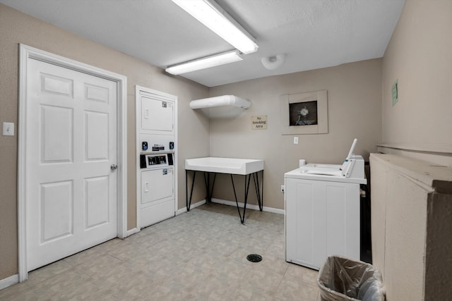 clothes washing area featuring washer and dryer, a textured ceiling, stacked washing maching and dryer, and sink