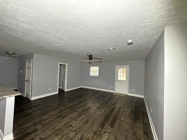 unfurnished living room with dark hardwood / wood-style floors, ceiling fan, and a textured ceiling