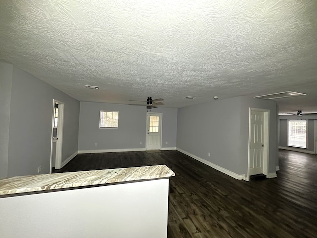 unfurnished living room with dark hardwood / wood-style floors, a healthy amount of sunlight, and a textured ceiling