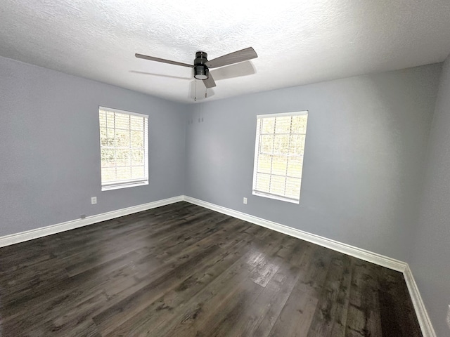 empty room with a textured ceiling, dark hardwood / wood-style flooring, and a wealth of natural light