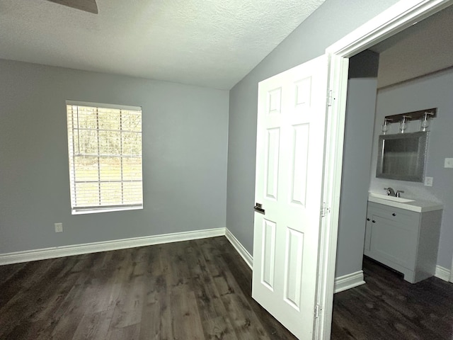 unfurnished bedroom featuring ceiling fan, sink, dark hardwood / wood-style floors, a textured ceiling, and lofted ceiling