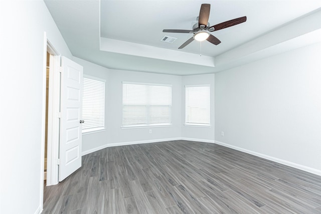 unfurnished room featuring ceiling fan, a raised ceiling, and dark wood-type flooring