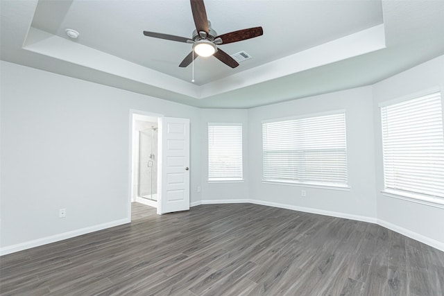 empty room with a tray ceiling, ceiling fan, and dark hardwood / wood-style flooring