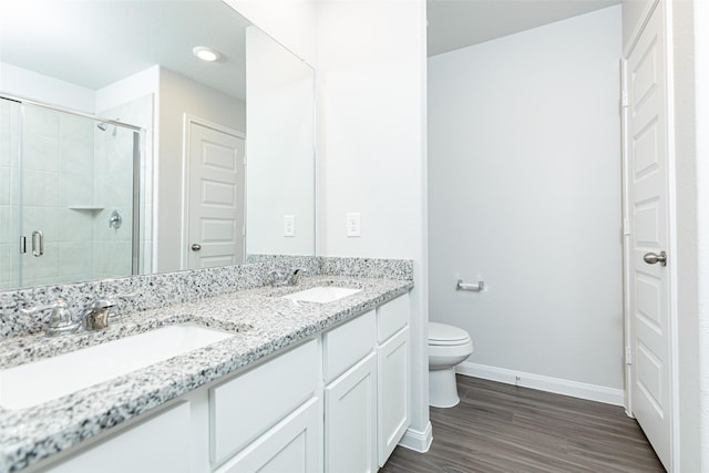 bathroom featuring a shower with door, vanity, hardwood / wood-style floors, and toilet