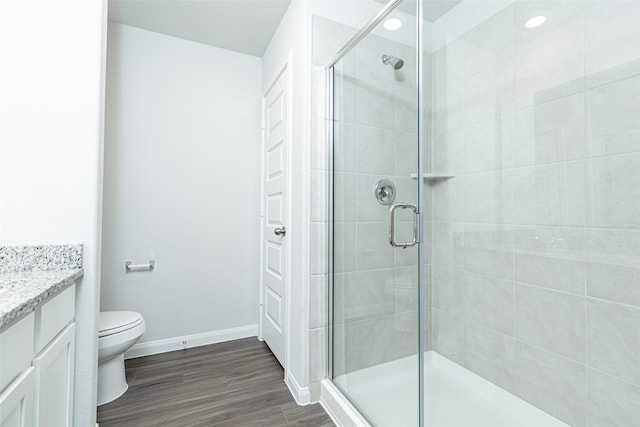 bathroom featuring wood-type flooring, vanity, toilet, and a shower with shower door