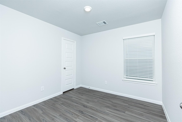 empty room featuring a textured ceiling and dark wood-type flooring