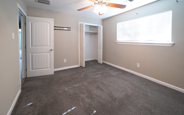 unfurnished bedroom featuring ceiling fan, dark carpet, and a closet