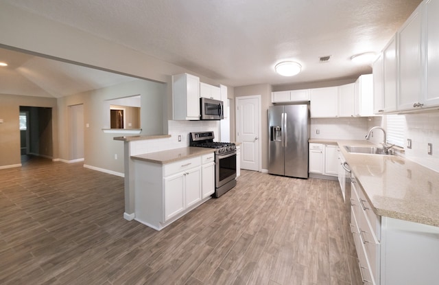 kitchen featuring decorative backsplash, stainless steel appliances, sink, hardwood / wood-style floors, and white cabinetry