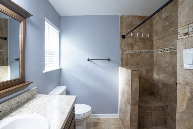 bathroom with a tile shower, tile patterned floors, vanity, and toilet