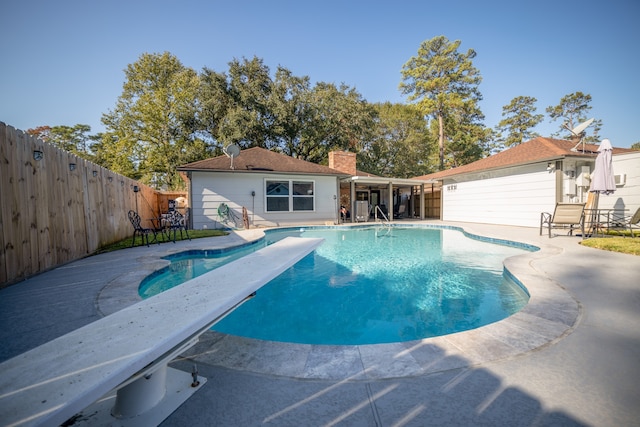 view of pool with a patio and a diving board