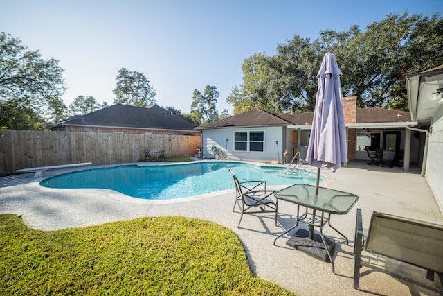 view of swimming pool featuring a patio and a diving board