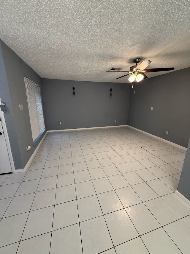 spare room featuring light tile patterned floors, a textured ceiling, and ceiling fan