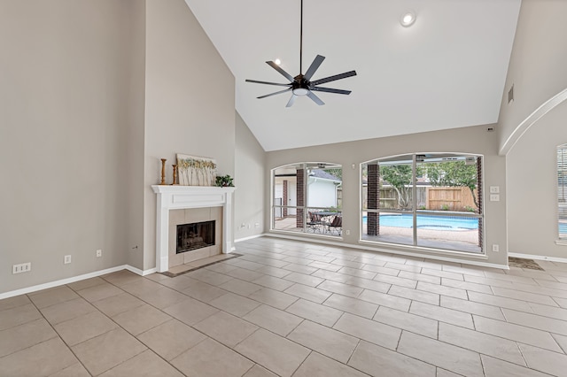 unfurnished living room with ceiling fan, light tile patterned floors, high vaulted ceiling, and a tiled fireplace