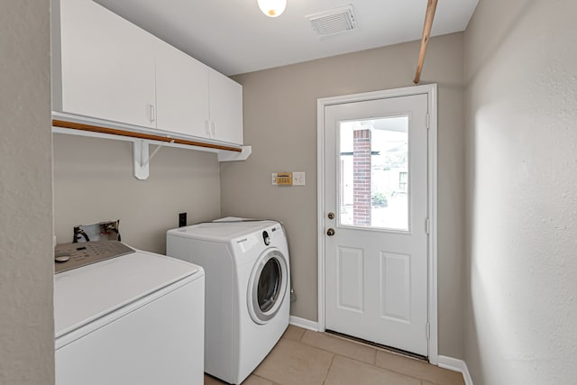 laundry room with washer and clothes dryer, light tile patterned floors, and cabinets