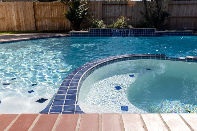 view of pool featuring pool water feature and an in ground hot tub