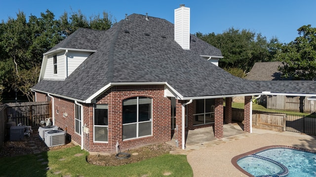 rear view of property with a fenced in pool, central AC, and a patio area