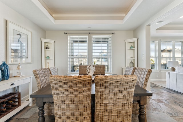 dining area with a tray ceiling and crown molding